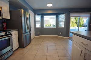 Kitchen with dark countertops, stainless steel range oven, white cabinetry, and light tile patterned flooring