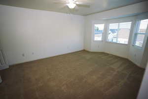 Empty room with dark carpet and a ceiling fan