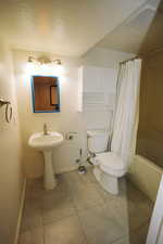Bathroom with shower / bath combo, a textured ceiling, and light tile patterned floors