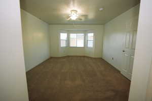 Spare room featuring dark carpet and a ceiling fan