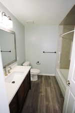 Full bath with dark wood finished floors, vanity, and shower / washtub combination