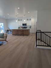 Kitchen with light countertops, white cabinets, open floor plan, pendant lighting, and brown cabinetry
