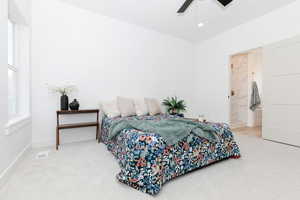 Primary bedroom with light colored carpet, ceiling fan, connected bathroom, and recessed lighting
