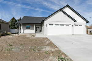 View of front of property with a porch, concrete driveway, an attached garage, board and batten siding, and a shingled roof
