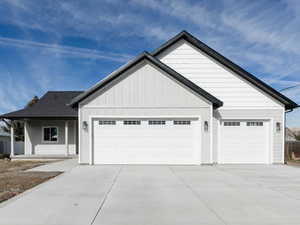 View of front of property with a porch, driveway, a garage, and board and batten siding