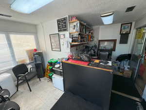 Home office featuring light floors and a textured ceiling