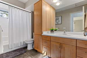 Full bathroom featuring shower / bath combination with curtain, vanity, and dark tile patterned flooring