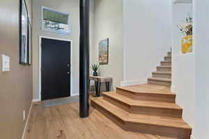 Foyer entrance featuring stairway, light wood-style floors, and a towering ceiling