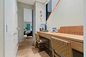 Work nook featuring built in desk and light wood-style floors