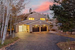 View of front of home featuring stucco siding, a chimney, driveway, a garage, and a balcony