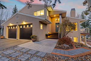 View of front of house featuring stucco siding, a chimney, concrete driveway, and an attached garage