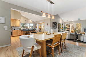 Dining area with light wood-type flooring, high vaulted ceiling, and recessed lighting