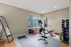 Workout area with light wood-type flooring and recessed lighting