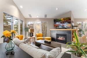 Living area featuring lofted ceiling, a glass covered fireplace, and recessed lighting