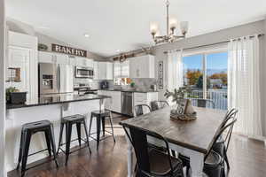 Dining room featuring vaulted ceiling, dark wood finished floors, recessed lighting, and a chandelier