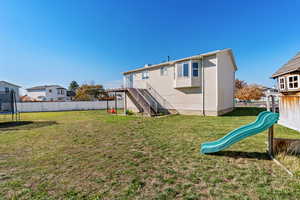 Rear view of house featuring a trampoline, stairway, a playground, and a deck