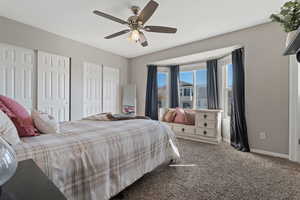 Carpeted bedroom with multiple closets and a ceiling fan