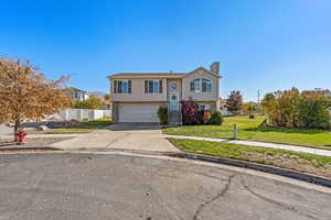 Split foyer home featuring driveway, a chimney, and a garage