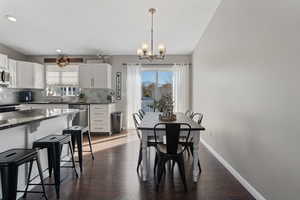 Dining room with dark wood finished floors, healthy amount of natural light, a chandelier, and recessed lighting