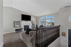 Living room with vaulted ceiling, a glass covered fireplace, and carpet flooring