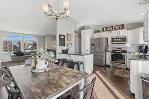 Dining room featuring lofted ceiling, a chandelier, recessed lighting, and dark wood-style floors