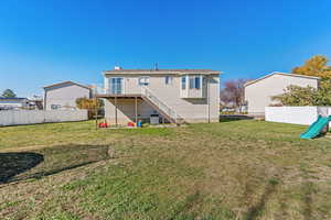 Back of property featuring stairs, a deck, and a playground