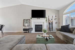 Carpeted living area with vaulted ceiling and a tile fireplace