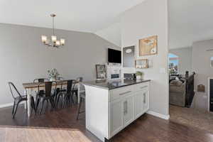 Kitchen featuring a peninsula, white cabinets, lofted ceiling, dark stone counters, and a breakfast bar