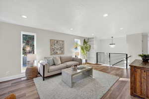 Living area with a textured ceiling, wood finished floors, recessed lighting, and a chandelier
