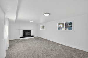 Unfurnished living room with carpet floors, a wood stove, healthy amount of natural light, and a textured ceiling