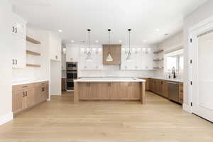Kitchen featuring open shelves, glass insert cabinets, tasteful backsplash, light wood finished floors, and white cabinets