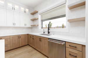 Kitchen featuring open shelves, decorative backsplash, dishwasher, and light wood-style flooring