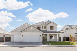 View of front of property featuring covered porch, decorative driveway, brick siding, an attached garage, and board and batten siding