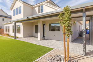 Rear view of property with stucco siding, a patio area, and a yard