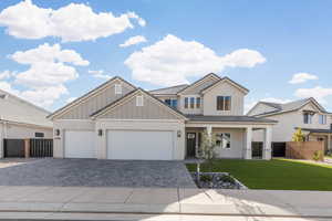 View of front of house with decorative driveway, a porch, board and batten siding, an attached garage, and brick siding
