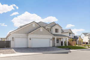 View of front of house featuring decorative driveway, brick siding, an attached garage, board and batten siding, and a porch