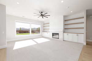 Unfurnished living room with a mountain view, recessed lighting, a tiled fireplace, a ceiling fan, and light wood-style floors