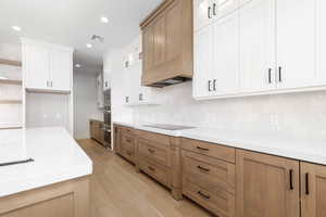 Kitchen featuring recessed lighting, light wood-type flooring, open shelves, light stone countertops, and white cabinetry