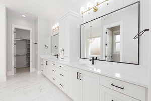 Full bathroom with double vanity, light marble finish floors, a spacious closet, a chandelier, and recessed lighting