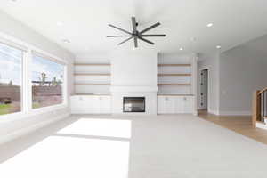 Unfurnished living room featuring a tile fireplace, recessed lighting, light carpet, a ceiling fan, and stairs
