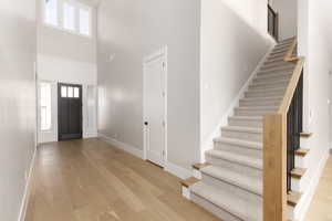 Entryway with light wood-type flooring, stairway, and a towering ceiling