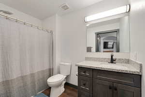 Full bath with a shower with curtain, vanity, and dark wood-type flooring
