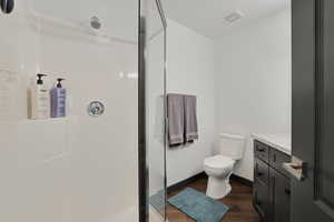 Bathroom with dark wood finished floors, vanity, and a shower stall