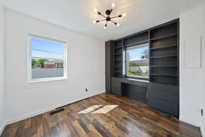 Bedroom featuring healthy amount of natural light, a chandelier, dark wood-type flooring, and built in desk