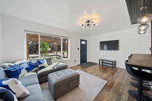 Living area with dark wood-style flooring and a chandelier