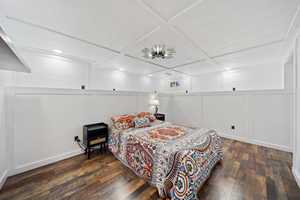 Bedroom with a decorative wall, dark wood-type flooring