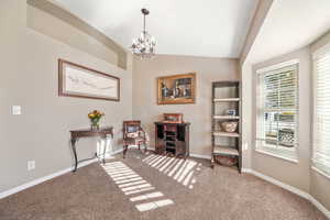 Living area with lofted ceiling, a chandelier, and carpet flooring