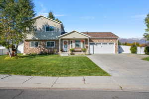 View of front of property with stone siding, covered porch, driveway, a garage, and a mountain view