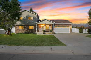 View of front of house featuring stone siding, covered porch, concrete driveway, and a garage