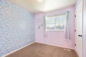 Unfurnished room with wallpapered walls, carpet floors, and an accent wall